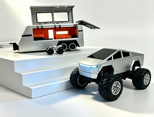 Silver angular RC truck beside an open camper trailer and miniature display prop