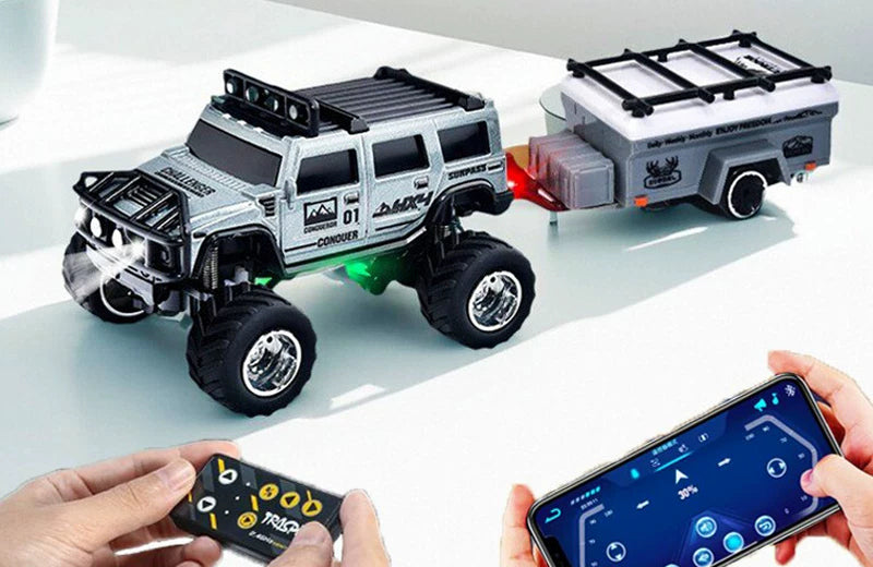 Silver mini RC SUV and camper displayed on a desk