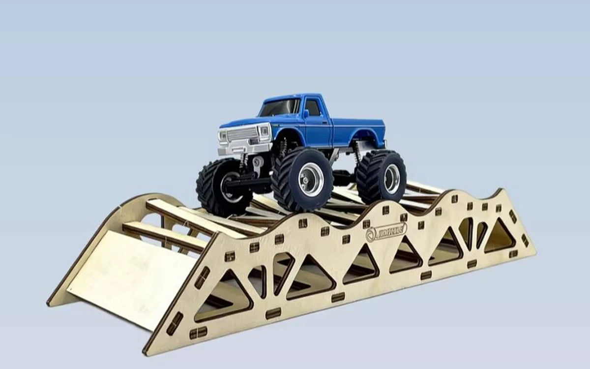 Side view of the blue RC pickup on a wooden obstacle