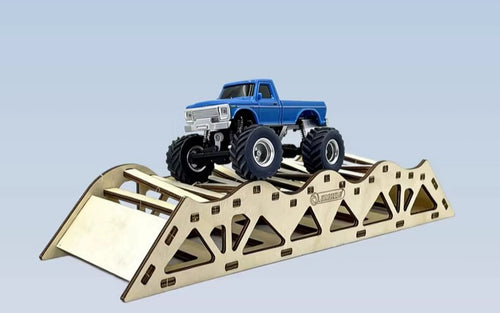 Side view of the blue RC pickup on a wooden obstacle