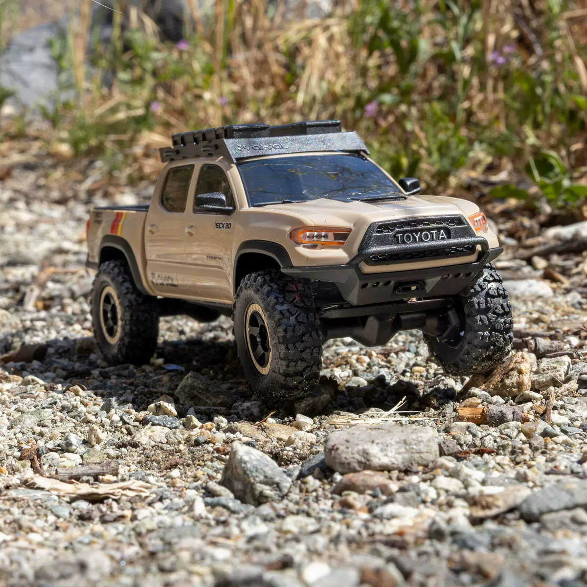 Brown Axial SCX30 Toyota Tacoma crawler on rocky outdoor terrain